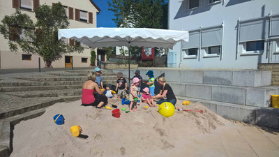 Sandplatz mit Spielzeug vor dem Rathaus